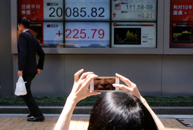 A woman takes a photo of an electronic board showing Japan's Nikkei average outside a brokerage in Tokyo, Japan June 2, 2017. (Photo by Toru Hanai/Reuters)