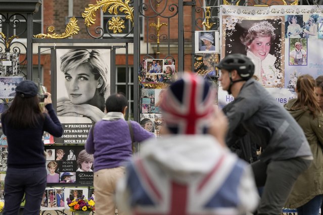 People stand in front of pictures of Princess Diana at the gates of Kensington Palace in London, Thursday, August 31, 2023. In the early hours of August 31, 1997, Diana, Princess of Wales died in hospital after being injured in a motor vehicle accident in a road tunnel in Paris. Her partner, Dodi Fayed, and the driver of the Mercedes-Benz W140, Henri Paul, were pronounced dead at the scene. Their bodyguard, Trevor Rees-Jones, survived with serious injuries. (Photo by Frank Augstein/AP Photo)