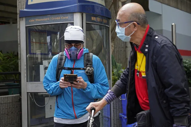 People wear face masks at a street in Hong Kong Tuesday, February 25, 2020. COVID-19 viral illness has sickened tens of thousands of people in China since December. (Photo by Vincent Yu/AP Photo)
