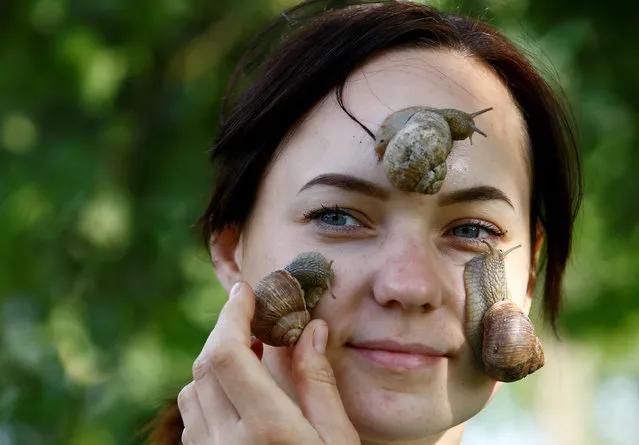 Victoria Rabkova, wife of the farmer Vladimir Rabkov, holds snails (Helix Pomatia) on her face at their  farm in the village of Dolginovo, Belarus August 22, 2017. (Photo by Vasily Fedosenko/Reuters)