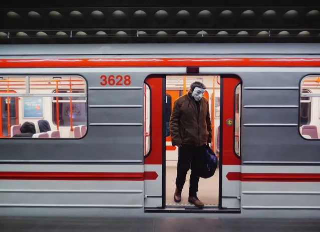 A man exits a subway car wearing a Guy Fawkes mask in Prague, Czech Republic on March 17, 2020. The day before, Prague's mayor said on Twitter: “On Prague public transport, it is mandatory to have a covered mouth and nose! Whether you have medical masks, self-made masks, or use a scarf, anything is better than nothing”. (Photo by Amos Chapple/Radio Free Europe/Radio Liberty)