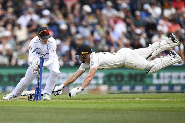 Glenn Phillips of New Zealand dives as England's wicketkeeper Ollie Pope knocks off the bails during play on the second day of the first cricket test between England and New Zealand at Hagley Oval in Christchurch, New Zealand, Friday, November 29, 2024. (Photo by Andrew Cornaga/Photosport via AP Photo)