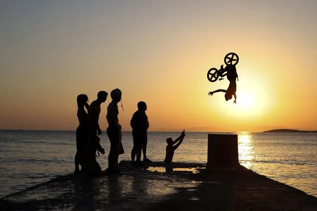 A biker performs tricks at Kavouri beach during a heatwave near Athens, Greece on July 24, 2022. (Photo by Stelios Misinas/Reuters)