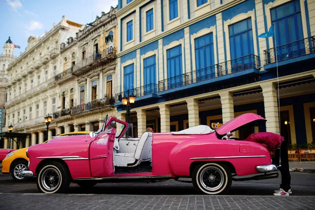 A vintage car driver checks his back lights as he waits for tourists in Havana, Cuba, September 14, 2017. (Photo by Alexandre Meneghini/Reuters)
