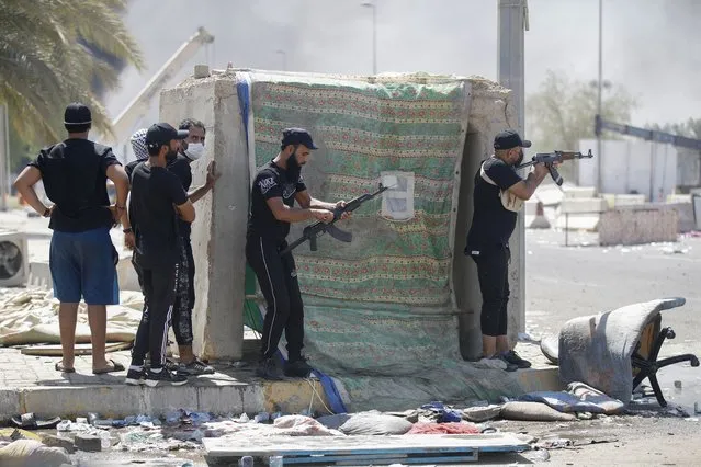 Armed members of Saraya al-Salam (Peace Brigade), the military wing affiliated with Shiite cleric Moqtada al-Sadr, are pictured during clashes with Iraqi security forces in Baghdad's Green Zone on August 30, 2022. Fighting between rival Iraqi forces resumed in Baghdad, where 23 supporters of Shiite leader Moqtada Sadr have been shot dead since Monday, according to the latest toll by medics. Clashes between Sadr's supporters and the army and men of the Hashed al-Shaabi, former paramilitaries integrated into the Iraqi forces, had calmed down overnight but resumed again on this morning. (Photo by Ahmad Al-rubaye/AFP Photo)