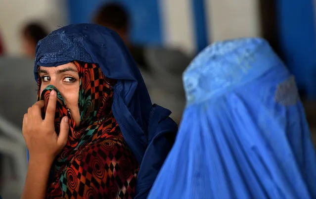 Afghan refugee women wait to board trucks at the United Nations High Commissioner for Refugees (UNHCR) repatriation centre on the outskirts of Peshawar on July 28, 2016, as they prepare to return to her home country after fleeing civil war and Taliban rule. Pakistan is home to 1.5 million registered and about as many undocumented Afghan refugees, with growing insecurity in Afghanistan impeding voluntary return programmes. (Photo by A. Majeed/AFP Photo)