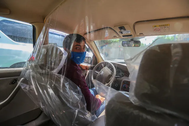 A taxi driver wearing a mask to protect sits inside a transparent partition to isolate himself from passengers on May 7, 2020 in Baku, Azerbaijan. The coronavirus outbreak has infected more than 3 million people across the world. Azerbaijan has reported 2127 cases of COVID-19 and 28 deaths. (Photo by Aziz Karimov/Getty Images)