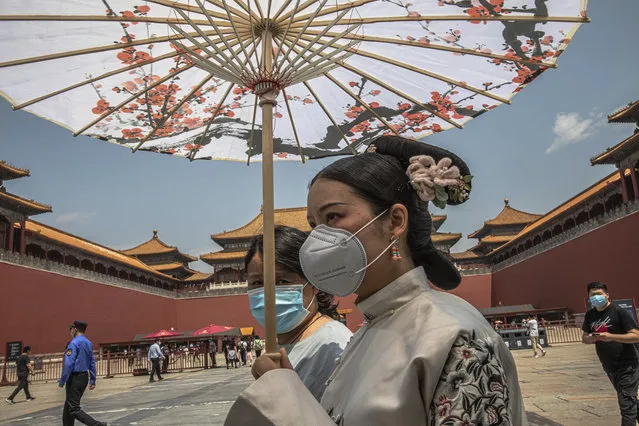 Women wearing protective face masks walk past the entrance to the Forbidden City on the first day of China's National People's Congress (NPC) in Beijing, China, Friday, May 22, 2020. (Photo by Roman Pilipey/Pool Photo via AP Photo)