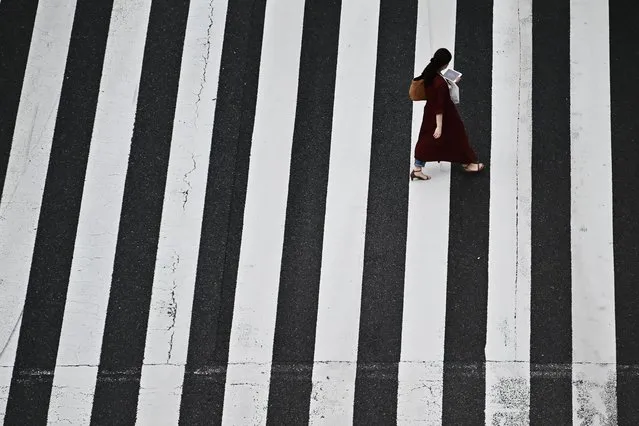 A woman crosses a street in Tokyo's Shinbashi area on May 15, 2020. (Photo by Charly Triballeau/AFP Photo)