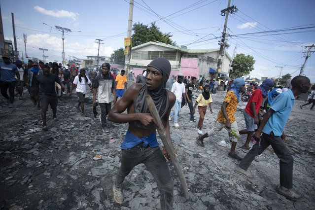 A protester carries a piece of wood simulating a weapon during a protest demanding the resignation of Prime Minister Ariel Henry, in the Petion-Ville area of Port-au-Prince, Haiti, Monday, October 3, 2022. (Photo by Joseph Odelyn/AP Photo)