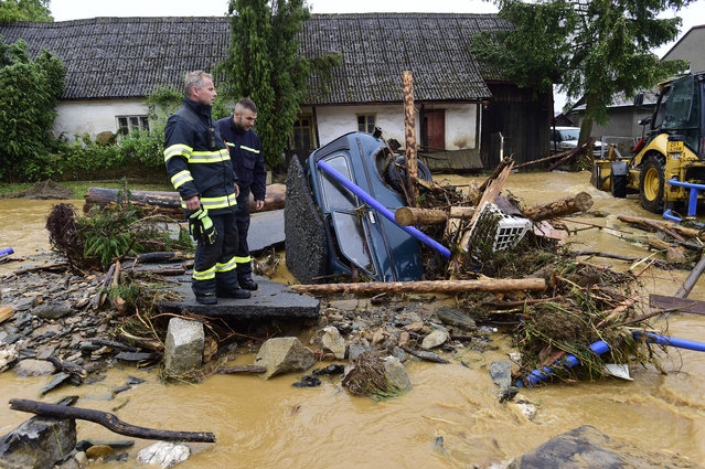 Firefighters look on a car trapped in a flooded area in Brevenec, the part of the village of Sumvald in the Olomouc region, Czech Republic, Monday, June 8, 2020. At least one person died, another is missing and dozens were rescued amid flash flooding in the northeastern Czech Republic. (Photo by Ludek Perina/AP Photo via CTK)
