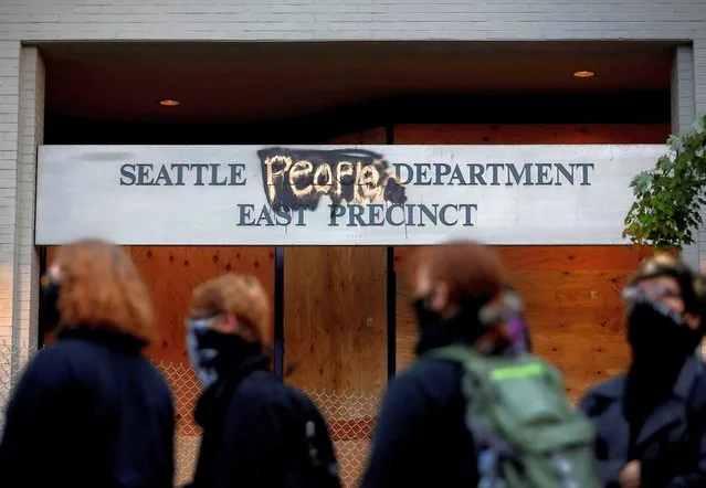 People stand in front of the Seattle Police Department's East Precinct sign, spray painted to replace “police” with “people” as the protesters established what they call an autonomous zone while continuing to demonstrate against racial inequality and call for defunding of Seattle police, in Seattle, Washington, U.S. June 9, 2020. (Photo by Lindsey Wasson/Reuters)