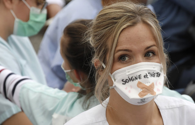 A health worker wearing a protective face mask with a handwritten message reading “Take care and shut up” as she takes part in a demonstration near the Regional Health Agency (ARS – Agence Regionale de la Sante) as part of a nationwide day of protests to demand better working conditions in Strasbourg, eastern France on June 16, 2020. (Photo by Frederick Florin/AFP Photo)