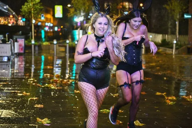Two girls run through the heavy rain as people head out to Wind Street in Swansea, Wales to celebrate Halloween on Monday, October 31, 2022. (Photo by Robert Melen)