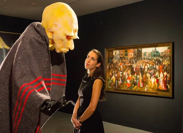 A Christie's employee views “Efficiency Men” by Thomas Schutte (left) and “A Market in a Town Square, with a Woman Punished for Adultery Beyond” by Marten van Cleve, part of “The Bad Shepherd” exhibition at Christie's Mayfair, from October 10 2014 to January 15 2015. The exhibition displays artworks by Brueghel in conversation with complementary artworks by post-war and contemporary artists. (Photo by Dominic Lipinski/PA Wire)