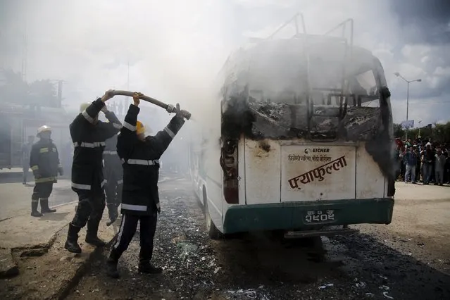 Firefighters try to douse fire set by unidentified protesters on a passenger bus during the nationwide strike, called by the opposition parties against the proposed constitution, in Kathmandu, Nepal September 20, 2015. (Photo by Navesh Chitrakar/Reuters)