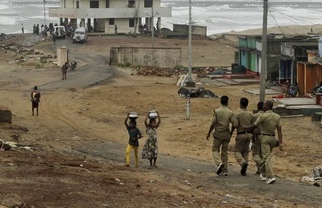 Indian children walk carrying water as policemen arrive to evacuate people on the Bay of Bengal coast at Gopalpur, Orissa, about 285 kilometers (178 miles) north east of Visakhapatnam, India, Sunday, October 12, 2014. (Photo by Biswaranjan Rout/AP Photo)