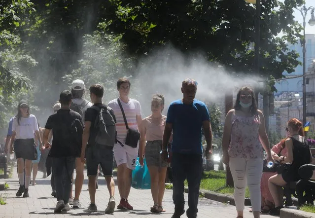 People walk through the mist made to cool people in gardens during hot summer weather in downtown Kyiv, Ukraine, June 27, 2020. Ukraine appeared on the WHO list of countries with a high rate of COVID-19 spread. The list also includes Albania, Azerbaijan, Bosnia and Herzegovina, Armenia, Northern Macedonia, Kazakhstan, Kyrgyzstan, Kosovo, Moldova and Sweden. (Photo by Sergii Kharchenko/NurPhoto via Getty Images)