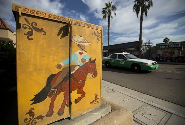 A taxi drives past a hand-painted utility box along the main street in the border town of San Ysidro, California September 2, 2015. (Photo by Mike Blake/Reuters)