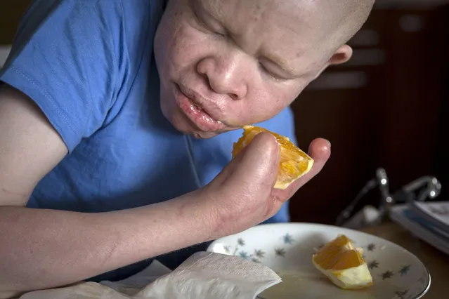 13-year-old Emmanuel Festo from Tanzania eats an orange as he does homework in Staten Island. (Photo by Carlo Allegri/Reuters)