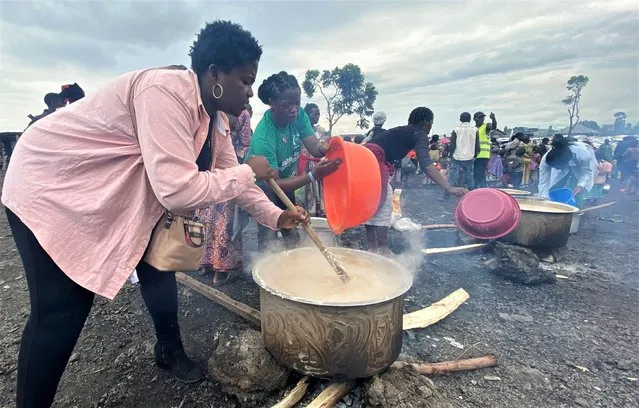 Volunteers prepare porridge for the internally displaced people at Kayembe primary school in Munigi camp near Goma, in the North Kivu province of the Democratic Republic of Congo on November 18, 2022. (Photo by Djaffar Sabiti/Reuters)