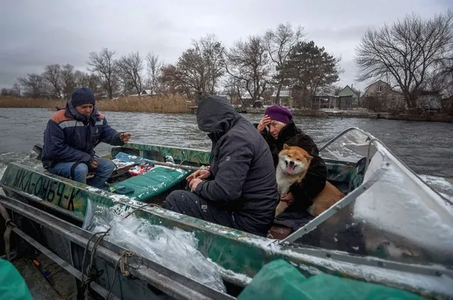 Olga Chpinyova, 81, and her dog Tosha are seen on a boat during their evacuation from a holiday village of Potyomkinskyi island on the Dnieper river near Kherson, on December 6, 2022, amid the Russian invasion of Ukraine. (Photo by Anatolii Stepanov/AFP Photo)