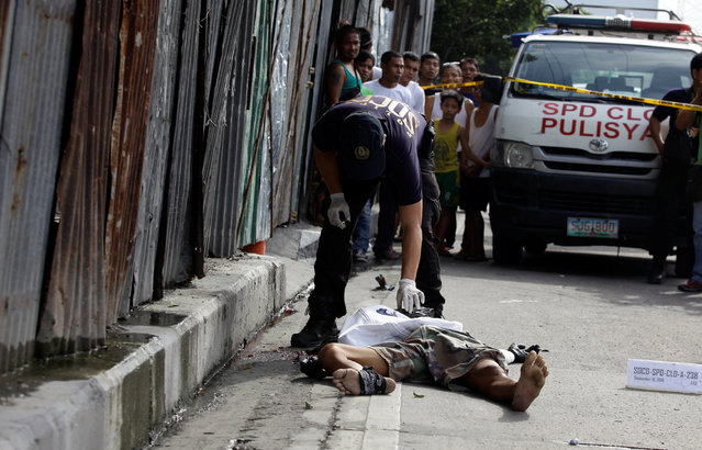 A policeman inspects the body of a man along a street in Pasay city, metro Manila in the Philippines September 15, 2016, whom the police said was a victim of a drug-related vigilante killing. Local media reported some 20 people were killed overnight in the Philippine capital on drug-related killings. (Photo by Czar Dancel/Reuters)
