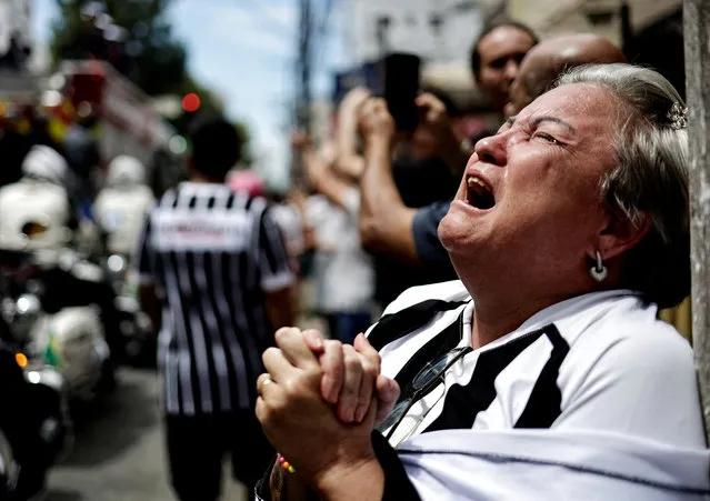 A mourner reacts as the casket of Brazilian soccer legend Pele is transported to the Santos' Memorial Cemetery during his funeral procession in Santos on January 3, 2023. (Photo by Ueslei Marcelino/Reuters)