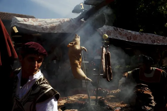 A pig hangs from a spit as it is roasted during the annual Cervantes market (Mercado Cervantino) in the hometown of famous Spanish writer Miguel de Cervantes, Alcala de Henares, Spain, October 9, 2015. The Mercado Cervantino, which represents a market and fair from the 16th and 17th centuries, takes place in the city's historic centre and commemorates Miguel de Cervantes' baptism, which took place on October 9, 1547. (Photo by Susana Vera/Reuters)