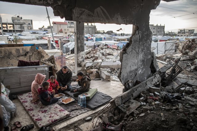 Palestinian Muhammad al-Durra, whose house was destroyed in the Israeli attack and who lost his wife, breaks his fast on the floor he prepares with his children in the wrecked house, in Rafah city of Gaza on March 20, 2024. Al-Durra (41) is spending Ramadan in his house, part of which was destroyed in the attacks. He has been forced to flee several times to protect their lives and currently lives in Rafah. (Photo by Jehad Alshrafi/Anadolu via Getty Images)