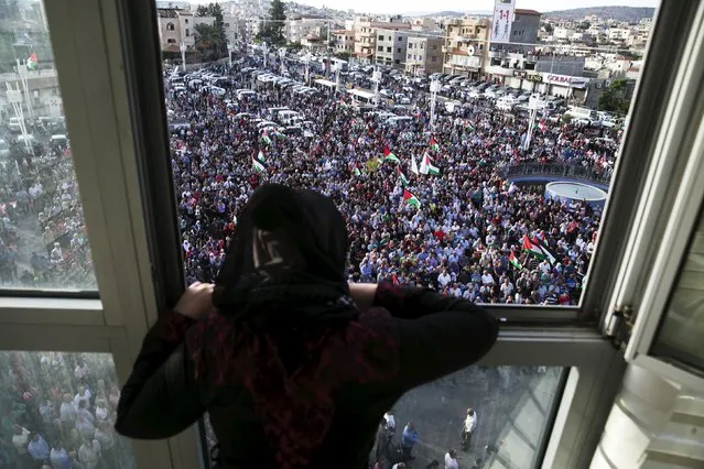 A woman stands at a window overlooking a pro-Palestinian demonstration in the northern Israeli town of Sakhnin October 13, 2015. Israel's leading Arab politician was in the middle of a television interview on a street in its biggest Arab city when the mayor, also an Arab, pulled up in his car and started shouting at him to leave. (Photo by Baz Ratner/Reuters)