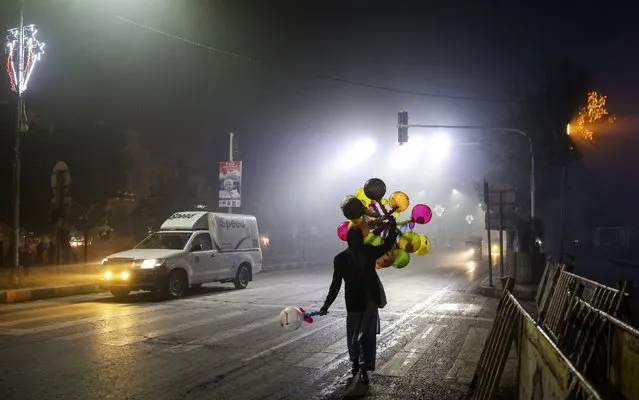 A street vendor selling balloons walks along a road shrouded in smog at night in Lahore, Pakistan on  November 14, 2017. (Photo by Asad Zaidi/Bloomberg)