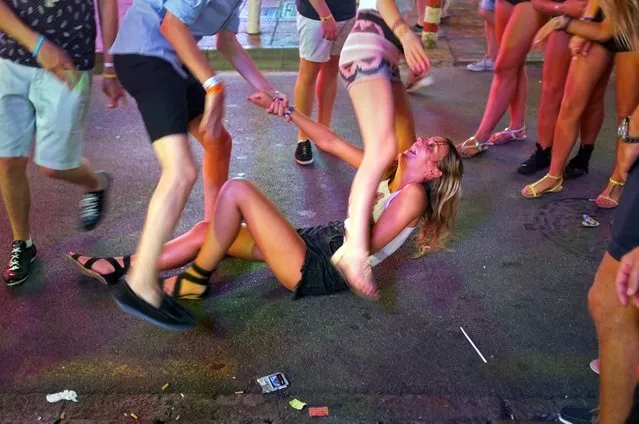 A girl laughs as she sits on the pavement in Punta Ballena street in Magaluf holiday resort in Calvia on the Spanish Mallorca Island on July 19, 2014. Known among some tourists as Shagaluf, the resort has suffered particularly bad press over the past 12 months after a video showing a Northern Irish teenage girl performing s*x acts on a group of men during a bar crawl went viral last summer. It is estimated 1 million Britons visit the region each year, bringing 800 million euros (866 million dollars) to the local economy, but the council is desperate to improve the reputation of destination, reported British journal The Guardian. (Photo by Jaime Reina/AFP Photo)