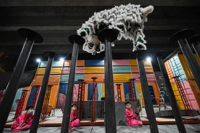 This picture taken on January 11, 2023 shows members of a lion dance troupe practising on high poles ahead of celebrations for the Lunar New Year of the Rabbit in Kuala Lumpur. (Photo by Mohd Rasfan/AFP Photo)