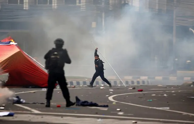 A demonstrator holds a stick during clashes with riot police officers following a protest against the new so-called omnibus law, in Jakarta, Indonesia, October 13, 2020. (Photo by Willy Kurniawan/Reuters)
