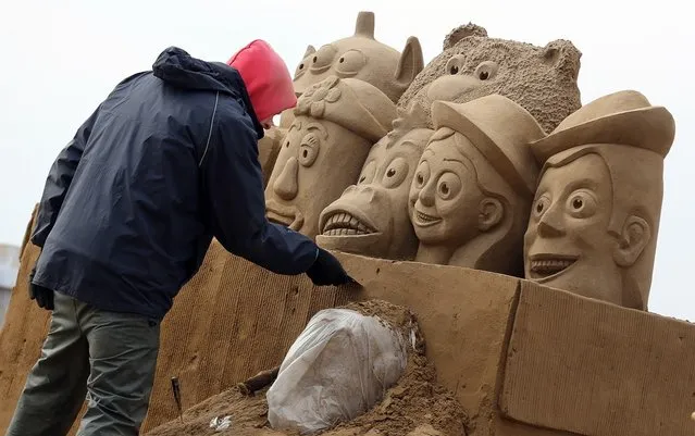 A sand sculptor works on a Toy Story themed sand sculpture as pieces are prepared as part of this year's Hollywood themed annual Weston-super-Mare Sand Sculpture festival on March 26, 2013 in Weston-Super-Mare, England. Due to open on Good Friday, currently twenty award winning sand sculptors from across the globe are working to create sand sculptures including Harry Potter, Marilyn Monroe and characters from the Star Wars films as part of the town's very own movie themed festival on the beach.  (Photo by Matt Cardy)