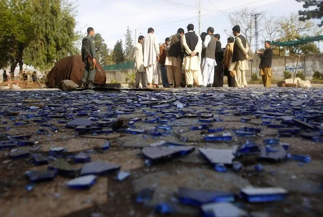 People gather near pieces of broken glass at the site of a suicide attack in Jalalabad March 26, 2013. Taliban suicide bombers killed at least five policemen in Afghanistan's restive east on Tuesday, officials said, in a three-hour attack that coincided with a visit to the country by U.S. Secretary of State John Kerry. (Photo by Parwiz/Reuters)