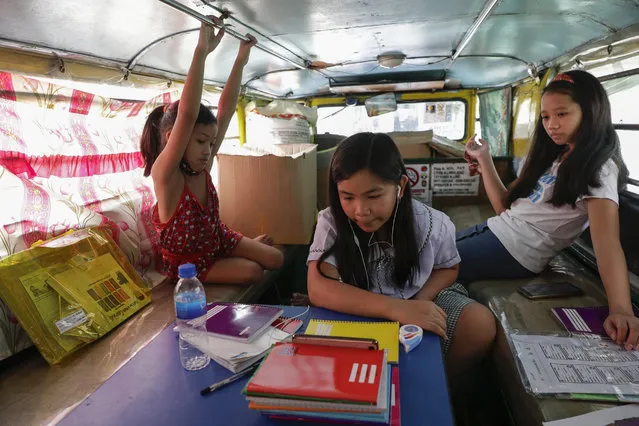 Grade school student Bhea Joy Roxas, center, uses a smart phone as she joins online classes while her friends observe inside a passenger jeepney at the Tandang Sora jeepney terminal in Quezon city, Philippines on Monday, October 5, 2020. Students in the Philippines began classes at home Monday after the coronavirus pandemic forced remote-learning onto an educational system already struggling to fun schools. The two students were tapping from a nearby store's wifi signal and have missed the flag raising ceremony due to poor internet connection. (Photo by Aaron Favila/AP Photo)