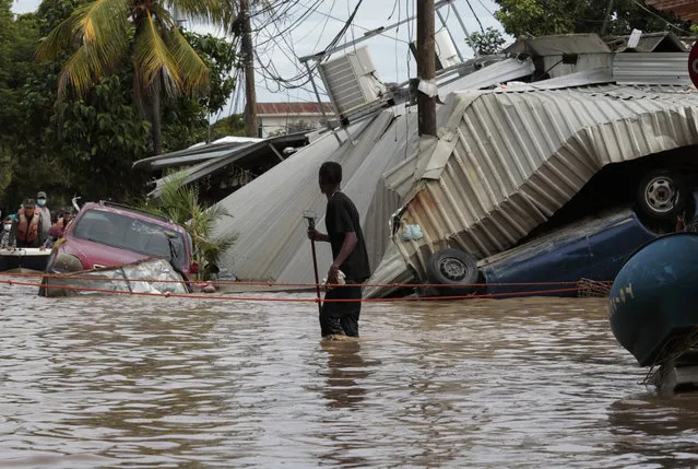 A resident walking through a flooded street looks back at storm damage caused by Hurricane Eta in Planeta, Honduras, Friday, November 6, 2020. As the remnants of Eta moved back over Caribbean waters, governments in Central America worked to tally the displaced and dead, and recover bodies from landslides and flooding that claimed dozens of lives from Guatemala to Panama. (Photo by Delmer Martinez/AP Photo)