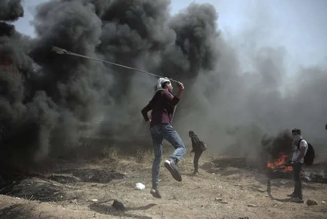 A Palestinian protester hurls stones at Israeli troops during a protest at the Gaza Strip's border with Israel, Friday, April 6, 2018. (Photo by Khalil Hamra/AP Photo)