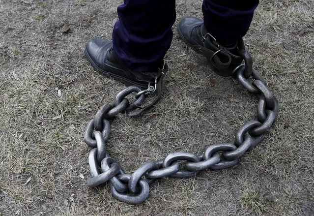 A Romanian policeman has his legs tied with a heavy chain during a rally held in front of the Romanian Parliament headquarters in Bucharest, Romania, 02 February 2022. About 1,500 policemen, prison guards and retired defense system employees from all over the country, gathered by fourteen trade union organizations, including Europol, joined a protest demanding the government to comply with the law on the remuneration of staff paid from public funds. Protesters marched through the center of Romania's capital asking for their risk supplementary payment and full pensions, demanding better working conditions and the employment of additional staff for solving specific tasks in a timely manner. (Photo by Robert Ghement/EPA/EFE)