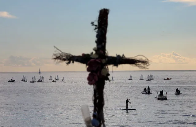 Boats sail behind a cross of a memorial for the victims of the fatal truck attack three months ago on the Promenade des Anglais, shortly before flowers and toys are removed, in NIce, France, October 16, 2016. (Photo by Eric Gaillard/Reuters)