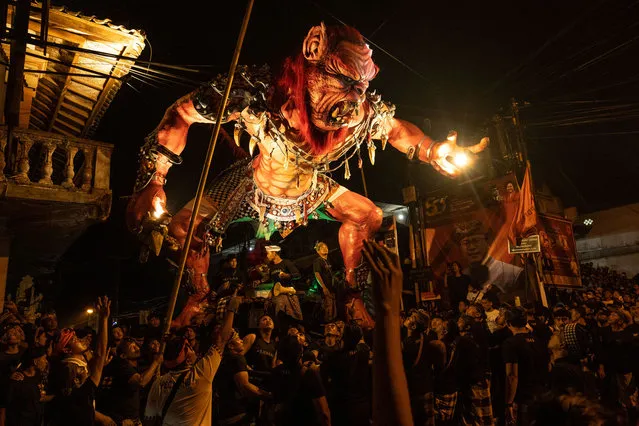 Balinese young men carry the ogoh-ogoh, the giant menacing-looking dolls during the ogoh-ogoh parade on the eve of Nyepi, the Balinese Hindu Day of Silence that marks the arrival of the new Saka lunar year on March 20, 2023 in Tegalalang Village, Gianyar, Bali, Indonesia. (Photo by Agung Parameswara/Getty Images)