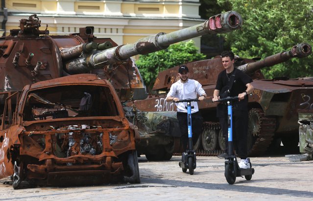 Youths ride scooters past destroyed Russian military equipment on Mykhailivska Square in the center of Kyiv on June 11, 2024, amid the Russian invasion in Ukraine. (Photo by Anatolii Stepanov/AFP Photo)