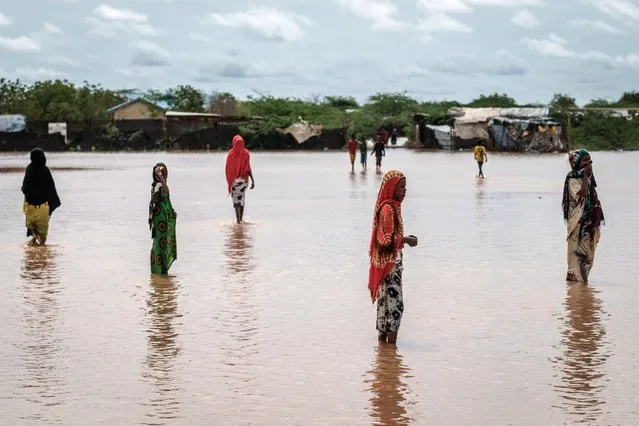 Refugees walk in floodwaters after a heavy rainy season downpour at the Dadaab refugee complex, in the north- east of Kenya, on April 17, 2018. The Dadaab refugee complex which has some 235269 refugees and asylum seekers in four camps about 80 kms from the Somali- Kenyan border was established in 1991, according to UNHCR camp population statistics in January 2018. (Photo by Yasuyoshi Chiba/AFP Photo)