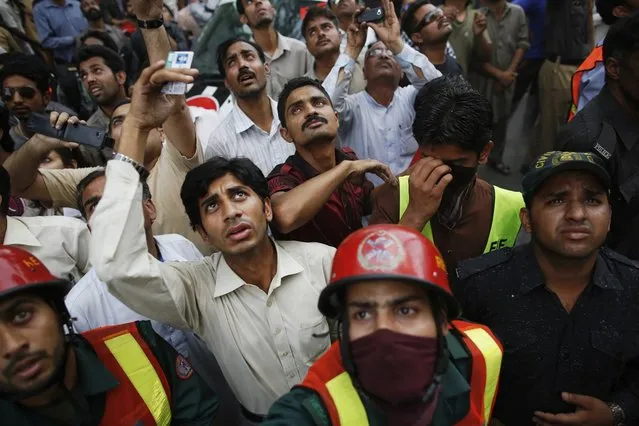 People react as rescue workers try to save people from a burning building in central Lahore May 9, 2013. (Photo by Damir Sagolj/Reuters)