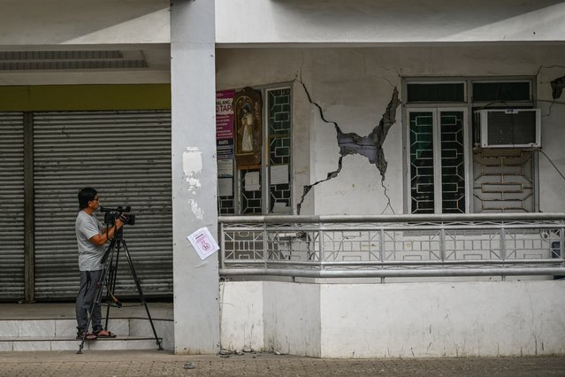 A cameraman films a damaged building in Manay, in the province of Davao Oriental on October 11, 2025, after two powerful quakes struck off the southern Philippines on October 10, killing at least eight people and triggering tsunami warnings. (Photo by Jam Sta Rosa/AFP Photo)