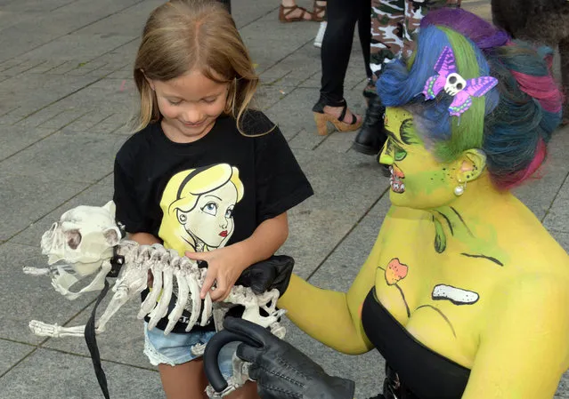 Rachel, who is dressed up as a zombie, lets a girl pet her dog skeleton in Ulm, Germany, 10 September 2016. Participants of the Zombie- Walk in Ulm try to haunt passersby with creative make up, costumes and props. (Photo by Stefan Puchner/DPA)