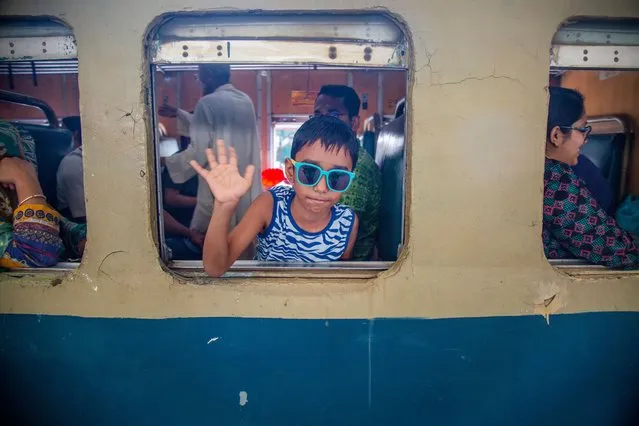 A boy waves after boarding a train to travel to his village ahead of Eid al-Fitr, in Dhaka, Bangladesh, 19 April 2023. Muslims around the world are preparing to celebrate Eid al-Fitr, marking the end of Ramadan. (Photo by Monirul Alam/EPA/EFE/Rex Features/Shutterstock)