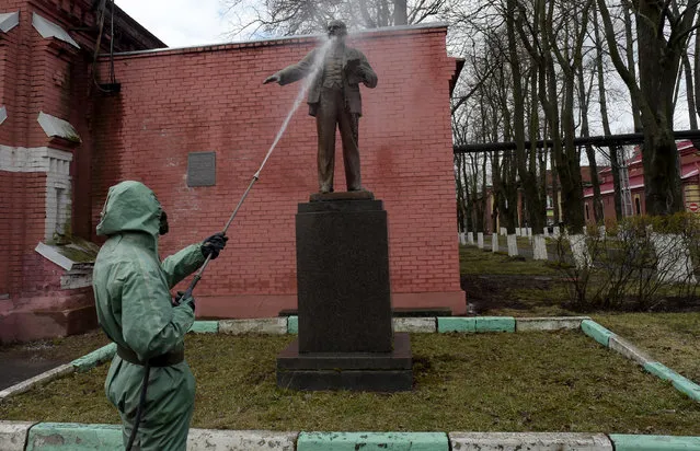 A Russian serviceman wearing a protective suit sprays disinfectant on a monument to the Soviet Union founder Vladimir Lenin while disinfecting an industrial area in Saint Petersburg on April 15, 2020, amid the COVID-19 coronavirus pandemic. (Photo by Olga Maltseva/AFP Photo)